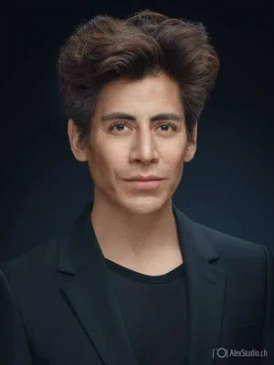 Contemporary headshot of a self-assured professional in a black blazer and crew-neck top, shaped by soft directional light against deep navy.