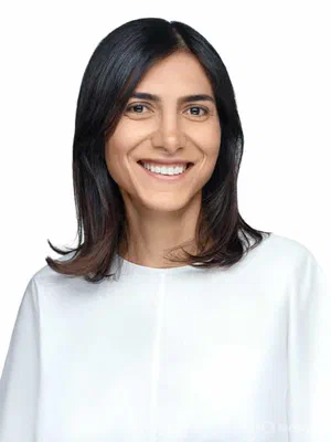 Fresh LinkedIn profile photo with an open smile, shoulder-length dark hair, and a minimalist white blouse on a bright seamless background.