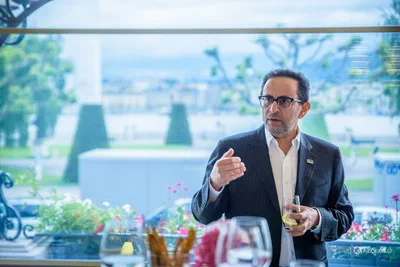 A speaker gestures while addressing guests near a bright window, captured naturally by Alex, a photographer based in Geneva, Switzerland.