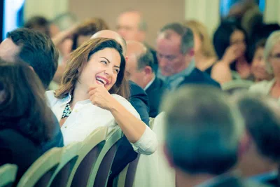 A seated attendee laughs openly among conference guests, a spontaneous reaction captured by Alex, a photographer in Geneva, Switzerland.