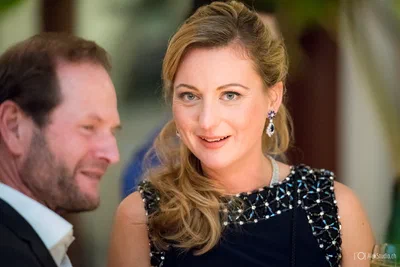 An elegantly dressed guest smiles during conversation at a formal gathering, rendered with flattering light and softly blurred event surroundings.