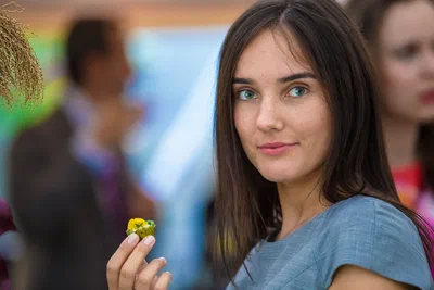 A guest holding a colorful canapé meets the camera with a relaxed expression during a reception, photographed by Alex in Geneva, Switzerland.