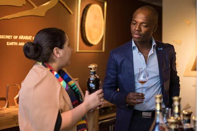 Two guests converse over a decanter and tasting glass in warm ambient light, an engaging candid from a refined corporate reception.
