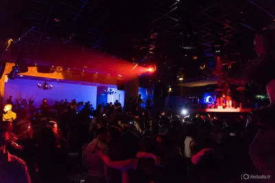 A packed nightclub crowd gathers beneath vivid red and blue lighting, creating an energetic wide-angle image of the evening's celebration.