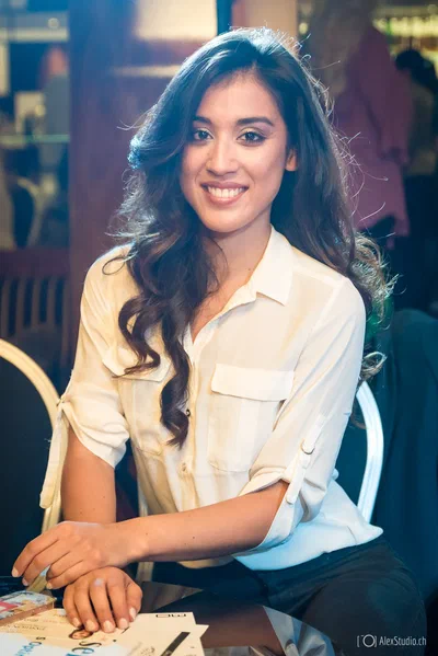 A smiling attendee sits poised at a table in a softly lit venue, photographed with natural warmth and an elegant shallow focus.